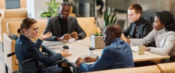 Group of colleagues excitedly discussing a new business venture at a large desk