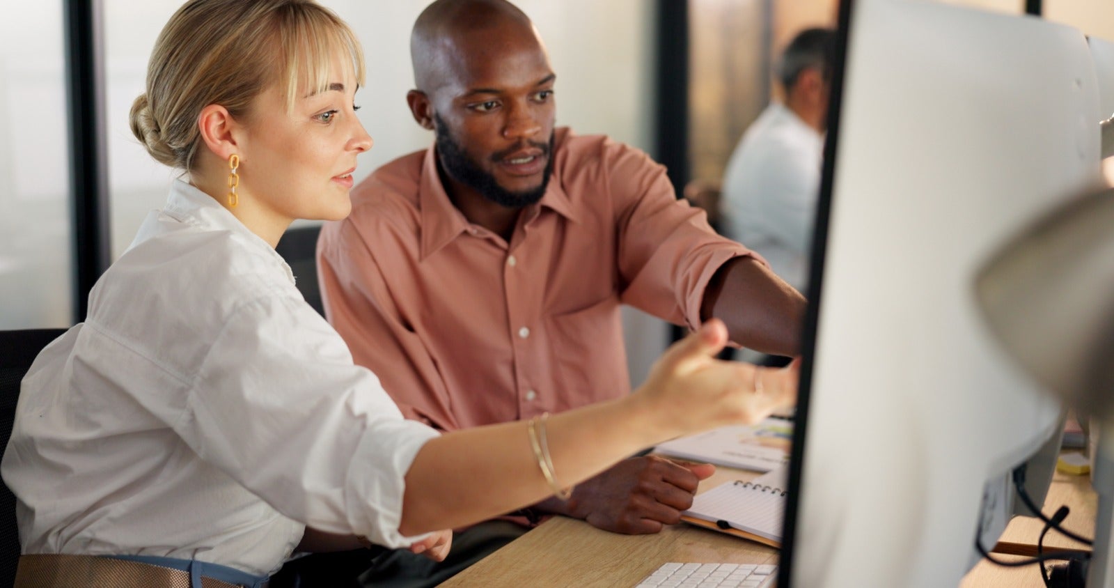 Female leader pointing to something interesting on computer to colleague