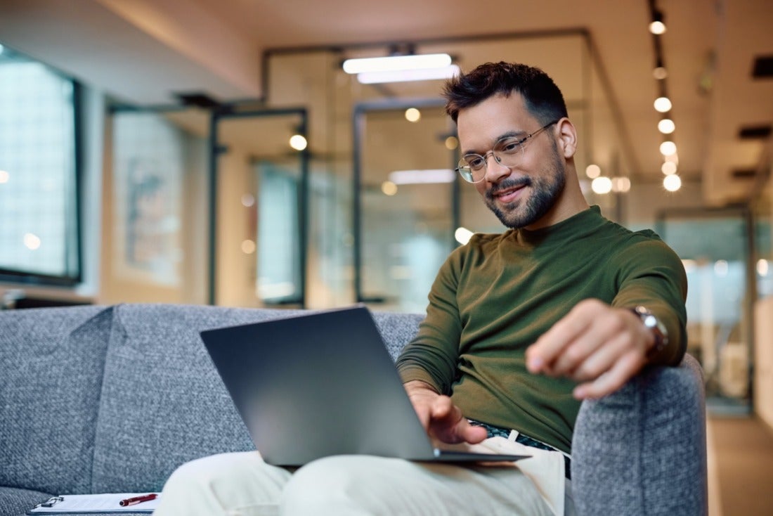 Young businessman looking happy and relaxed at his computer