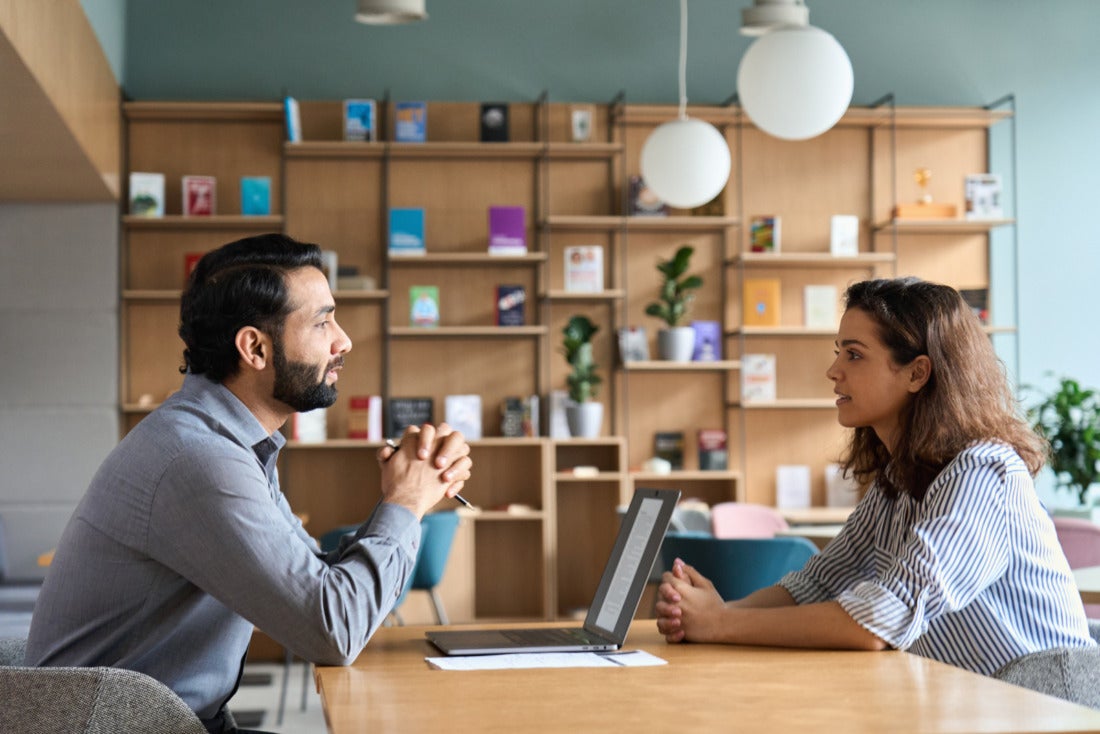 Business leader having a serious conversation with employee at an office desk