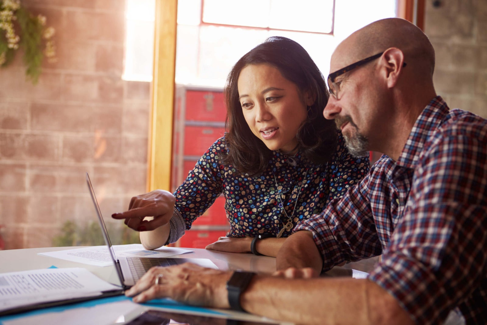 business colleagues discuss work project at desk with laptop
