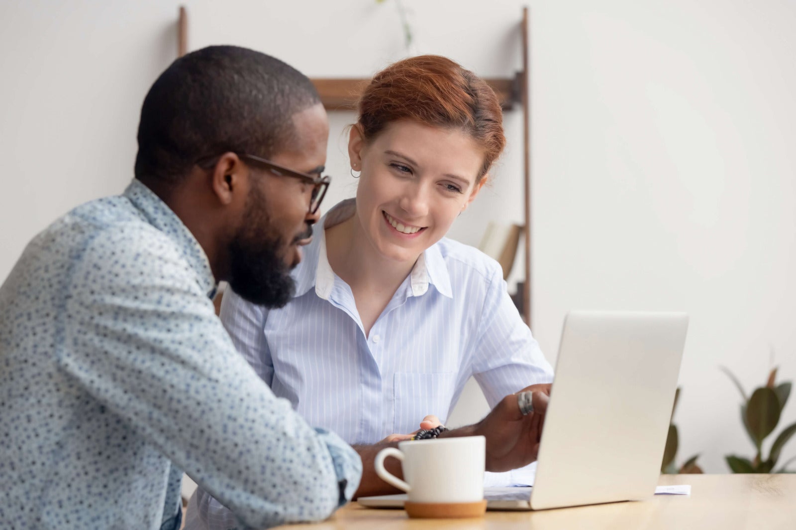 two coworkers look at lapto together with coffee