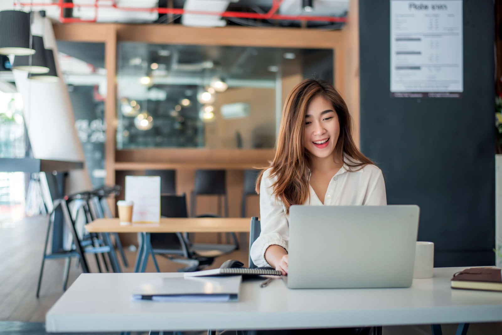young businesswoman smiles while working on laptop
