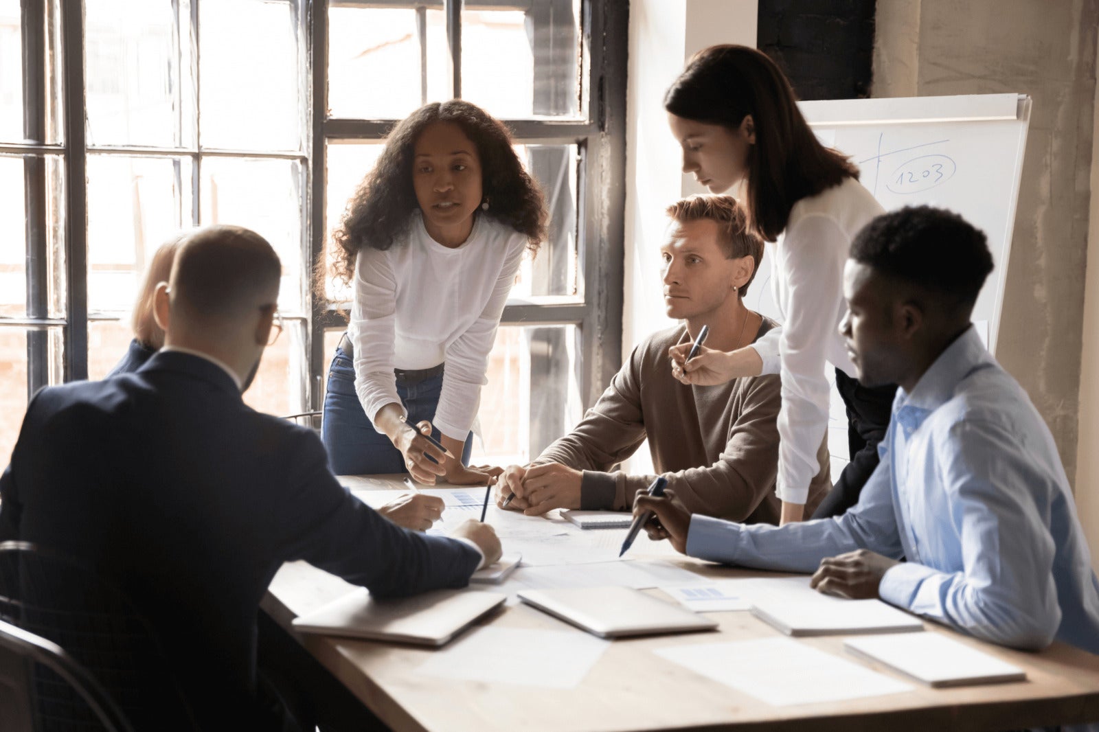 diverse business team liaises on work project around office table