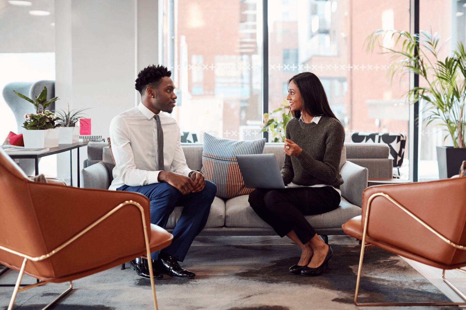 hiring manager speaks with candidate on office couch