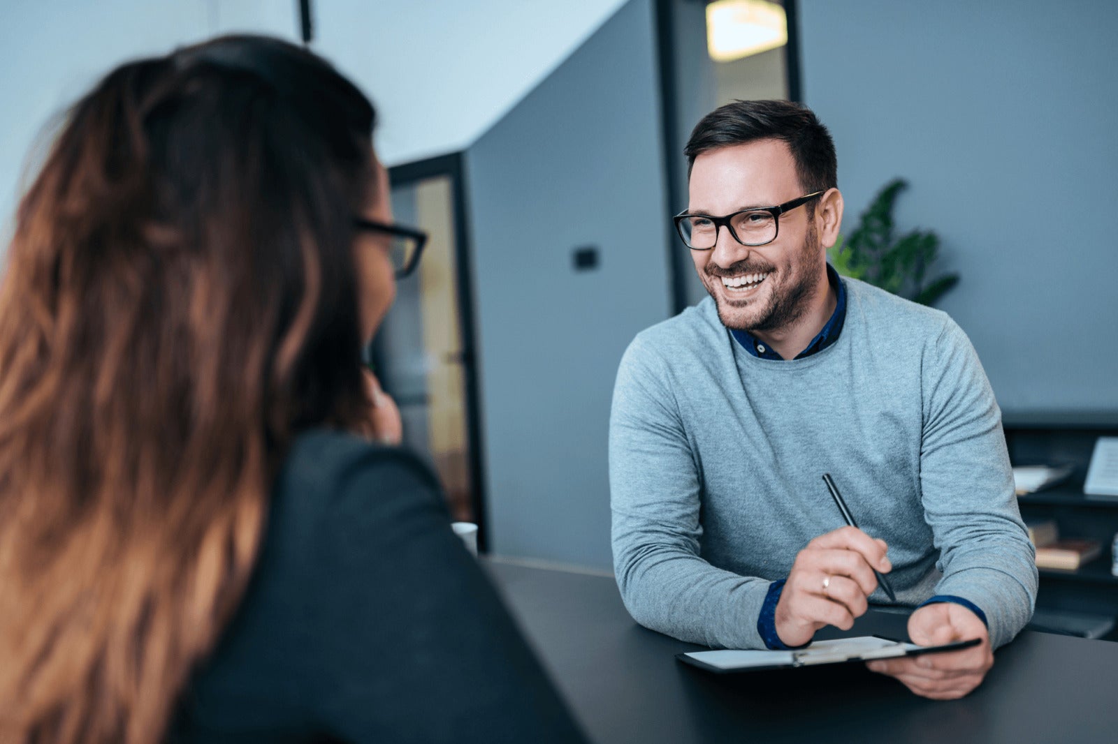 smiling hiring manager asks job candidate question during interview