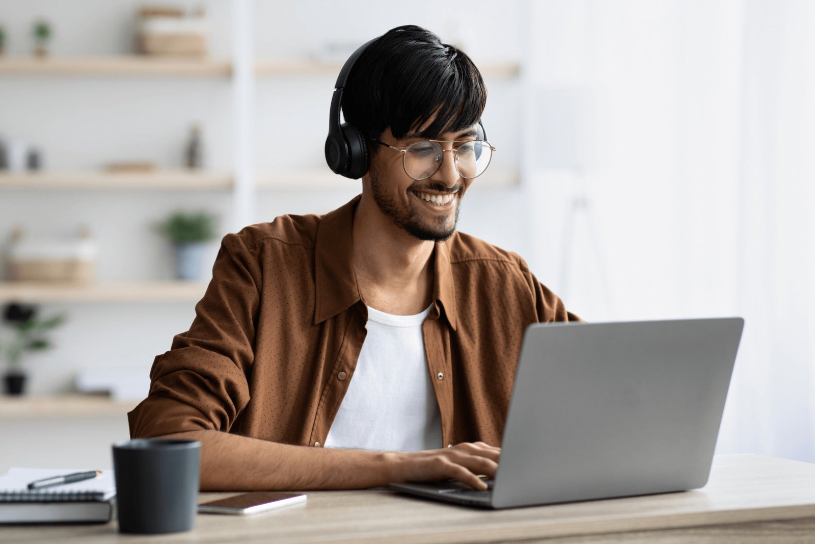 young casually dressed employee works on computer with headpones on