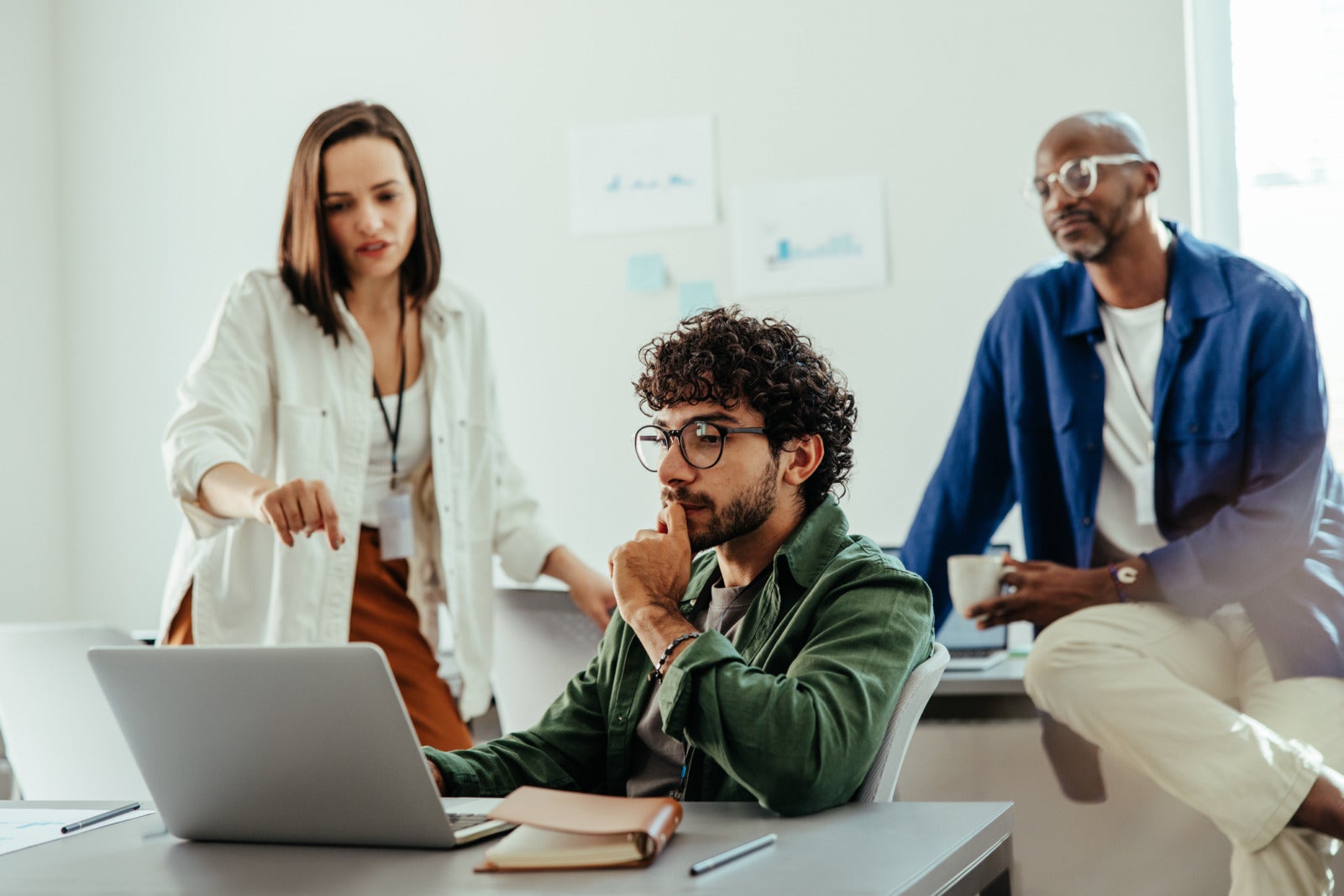 Diverse business team collaborating on a project at the office. Group of professionals brainstorming and discussing ideas around a laptop.