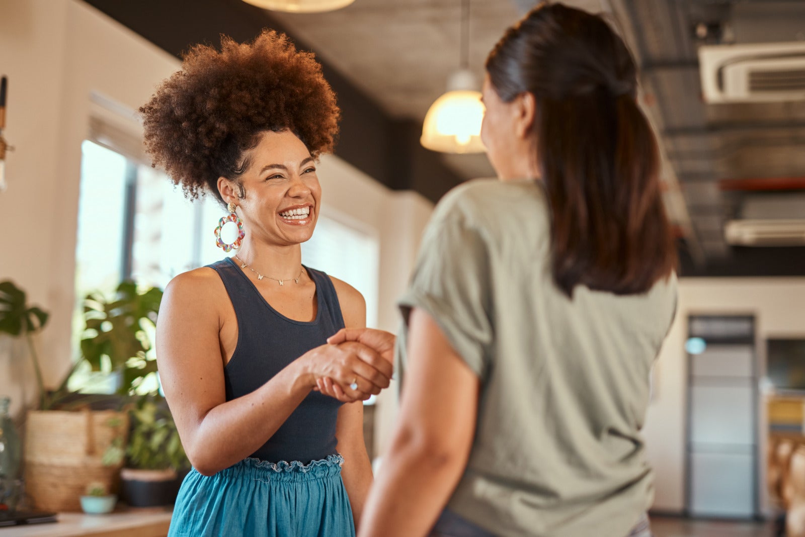 eautiful mixed race creative business woman shaking hands with a female colleague. Two young female african american designers making a deal. A handshake to congratulate a coworker on their promotion.